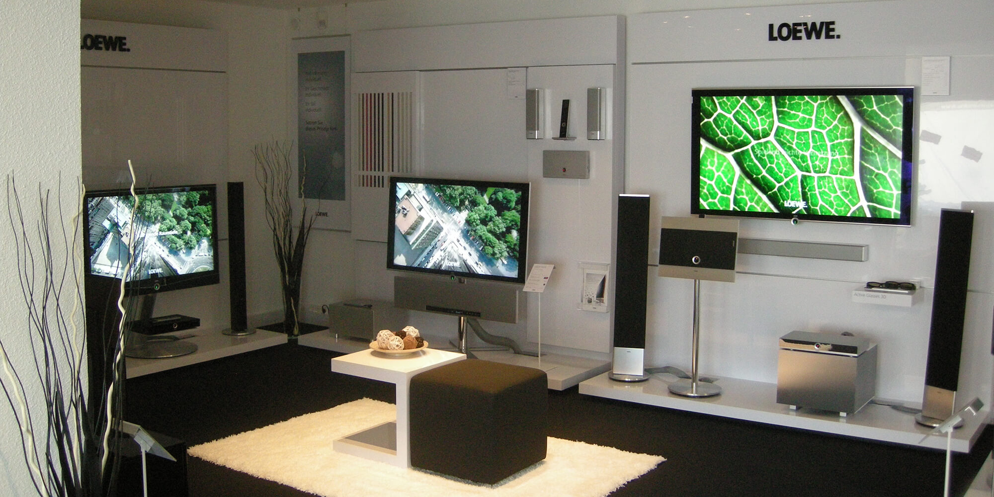 Unser Ausstellungsraum mit drei Fernsehern und Heimkinoanlage in elegantem, minimalistischem Design.