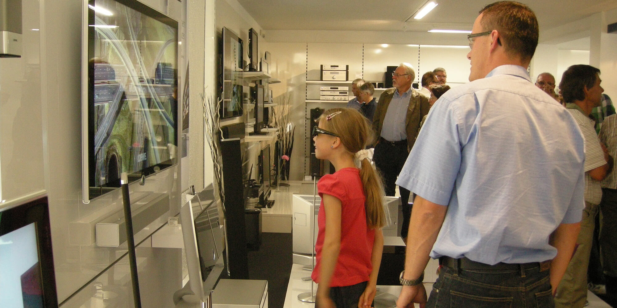 Ein Mädchen mit 3D-Brille schaut auf einen Fernseher in unserem Elektronikgeschäft.